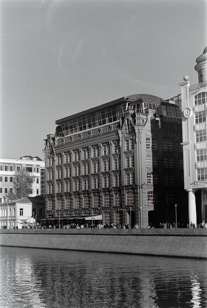Striking grayscale photograph of classic urban buildings along a river embankment.